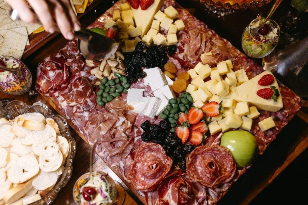 Tabla de quesos, jamón y embutidos con fresas, ciruelas pasas, orejones y frutos secos para una mesa de Navidad